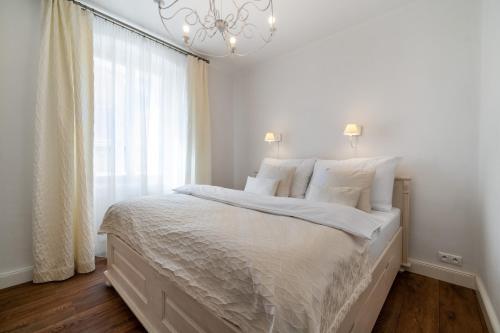 a white bedroom with a large bed and a chandelier at Boutique hotel Soukeníkův dům in Kutná Hora