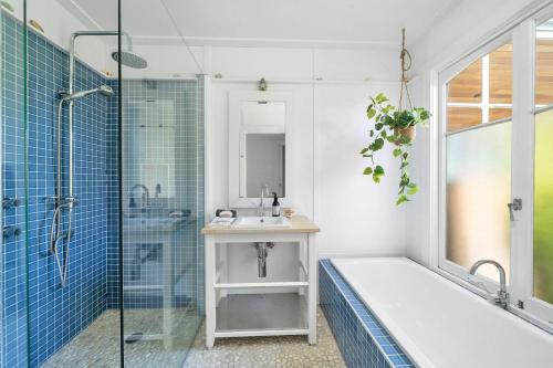 a bathroom with a tub and a sink and a shower at Avalon vintage beachside family getaway in Currarong