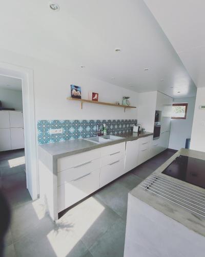 a large kitchen with white cabinets and a sink at De Veldmuis, met mooie speelhoek en speelhuis in Koksijde