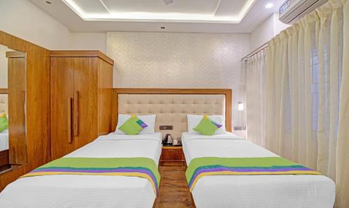 two beds in a hotel room with white and green at Treebo White Inn in Bengaluru