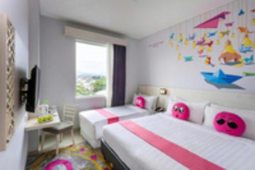 a bedroom with two beds and a desk and a window at favehotel Malang in Malang
