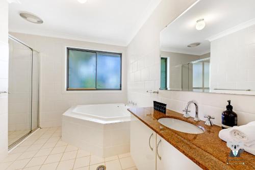 a bathroom with a sink and a toilet and a mirror at KOZYGURU | Westleigh | Spacious Home with 4 Beds in Thornleigh