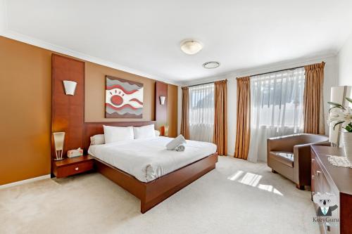 a bedroom with a bed and a desk and a chair at KOZYGURU | Westleigh | Spacious Home with 4 Beds in Thornleigh