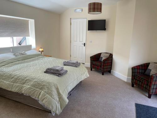 um quarto com uma cama e 2 cadeiras e uma televisão em The Old Kitchen em Burwarton