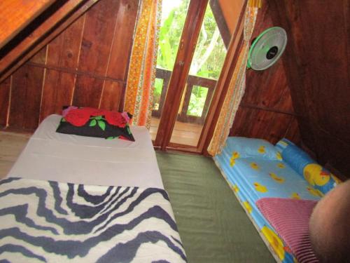 Habitación pequeña con 2 camas y ventana en Balian Camp penginapan, en Tuk Tuk