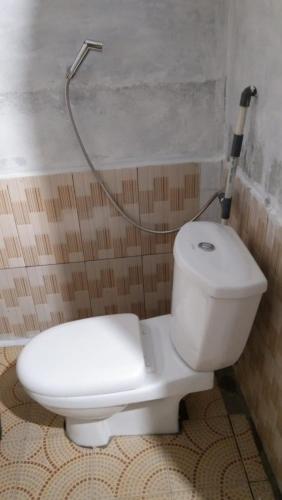 a white toilet in a bathroom with a hose at Balian Camp penginapan in Tuk Tuk