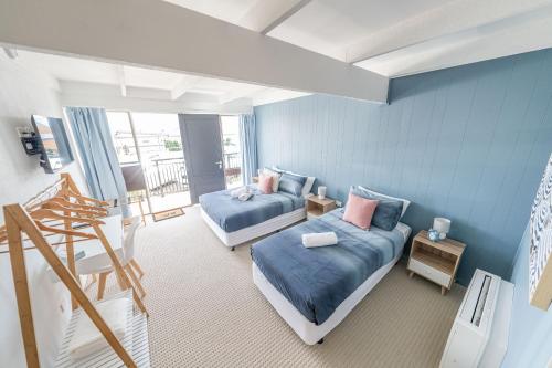 een blauwe kamer met 2 bedden en een trap bij Coast Motel Eden in Eden