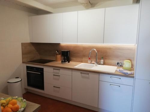 uma cozinha com armários brancos e um lavatório em Maison Trucchi em Menton