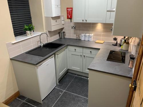 a kitchen with white cabinets and a sink at Meg's Den in Hebden Bridge