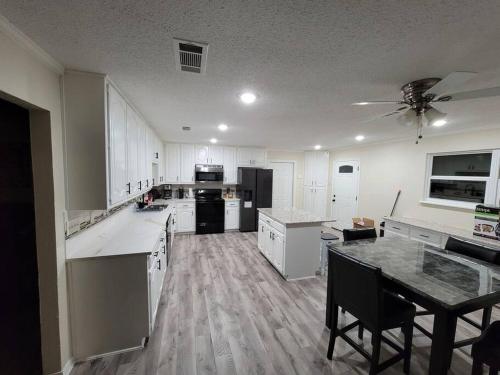 a large kitchen with white cabinets and a table at Modern 10 Acre Horse Ranch-Walk to Lake Ray Robert in Pilot Point