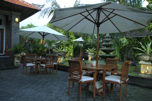 an outdoor patio with tables and chairs with umbrellas at Kubu Garden Suites & Villas Nusa Dua in Nusa Dua