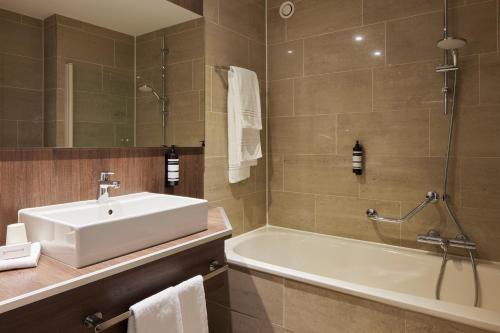a bathroom with a sink and a bath tub at Auberge Du Bonheur in Tilburg