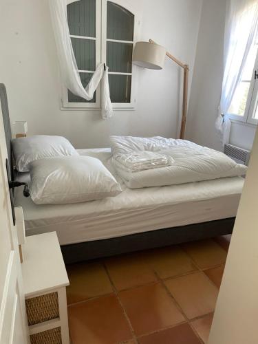 Cette chambre comprend un lit avec des oreillers blancs et une fenêtre. dans l'établissement Villa La Verne, à La Seyne-sur-Mer