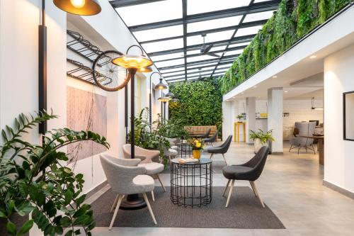 un vestíbulo con sillas, mesas y plantas en BY14 TLV Hotel, en Tel Aviv