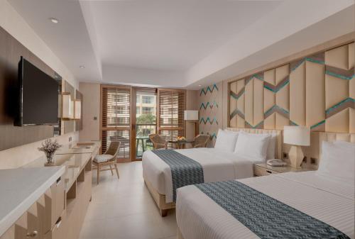 a hotel room with two beds and a desk and a television at Henann Tawala Resort in Panglao