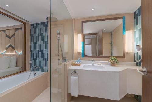 bagno con lavandino, vasca e specchio di Henann Tawala Resort a Panglao