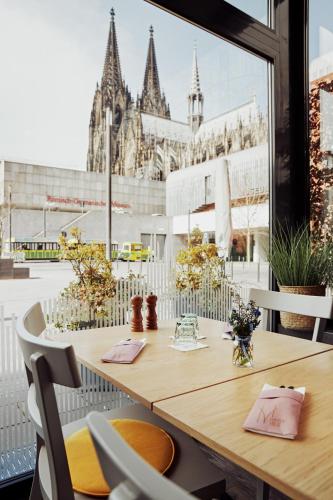 a table with chairs and a view of a building at Hotel Mondial am Dom Cologne MGallery in Cologne