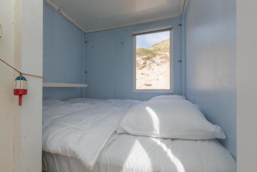 een slaapkamer met een wit bed en een raam bij Slaapstrandhuisje 182, Dishoek in Dishoek