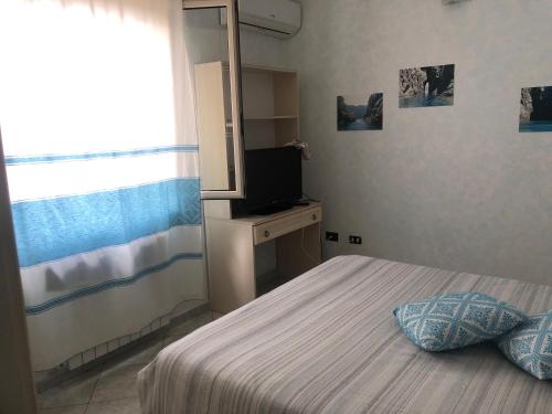 a small bedroom with a bed and a television at Villa di Cristina in Masainas