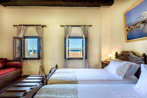 a bedroom with two beds and a couch and windows at Porto Del Colombo Traditional Boutique Hotel in Chania