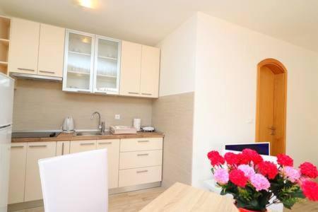 a kitchen with a vase of red flowers on a table at Apartments Seafront Silence in Trstenik
