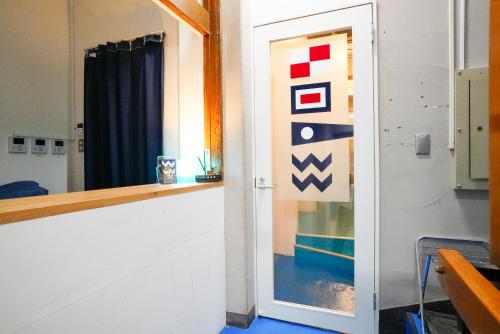 um quarto com uma porta com uma janela e um espelho em Wharf Inn em Yokohama