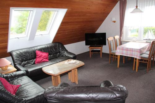 een woonkamer met een leren bank en een tafel bij Ferienwohnung Skipper in Dornumersiel