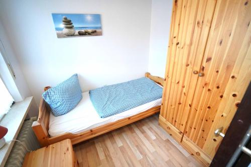 ein kleines Zimmer mit einem Bett mit blauen Kissen in der Unterkunft Ferienwohnung Käp` tns in Dornumersiel