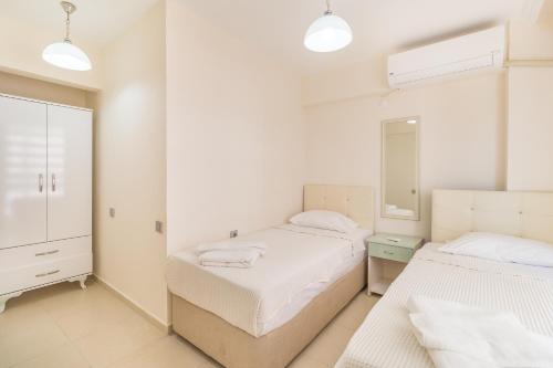 a white bedroom with two beds and a mirror at Apartments Near to City Center and Beach in Marmaris
