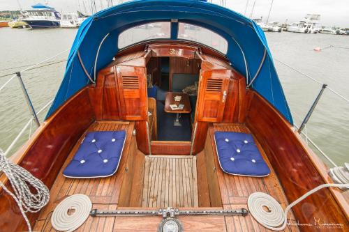 a wooden boat with blue seats in the water at Jachta " Džaladūta" in Nida