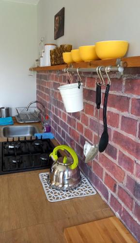 a kitchen with a brick wall with a pot and utensils at Domek Wilamów in Wilamów