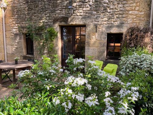 a garden with flowers in front of a stone building at La Closerie de Baneuil in Baneuil