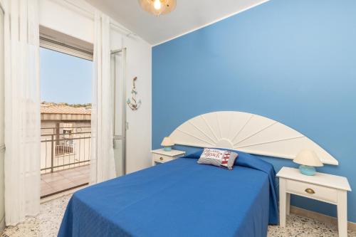 a blue bedroom with a large bed and a balcony at Coastal Home in Santa Maria Navarrese