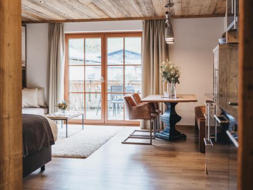 a bedroom with a bed and a table and a window at VAYA Kaprun inklusive Zell am See Kaprun Sommer Karte in Kaprun