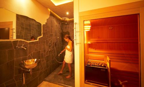 a woman standing in a bathroom with a shower at Engadiner Apartments & Wines in Montagna