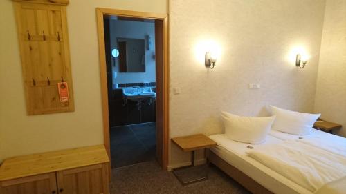a bedroom with a bed and a bathroom with a sink at Hotel Kapelle Bed & Breakfast in Bad Liebenstein