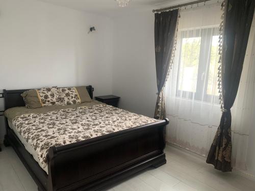 Un dormitorio con una cama y una ventana con cortinas. en Sonte Residence, en Hăulişca