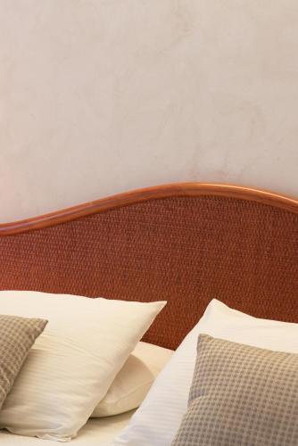 a bed with a wooden headboard and white pillows at Hotel Negresco in Lido di Jesolo