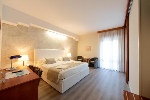 a hotel room with a bed and a desk and a room at Hotel Negresco in Lido di Jesolo
