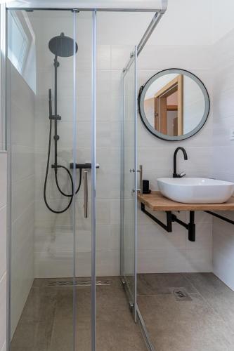 a bathroom with a shower with a sink and a mirror at Luxury Landing in Cres