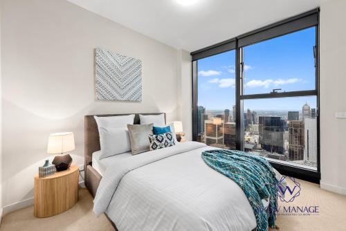 a bedroom with a bed and a large window at WOW Apartment on Collins in Melbourne