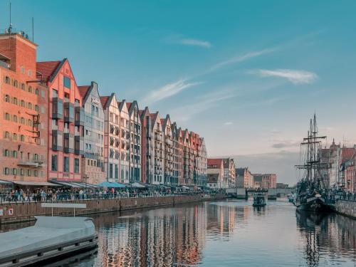 a city with buildings and a river with a boat at Apartamenty DEO Plaza VIP by Rent like home in Gdańsk