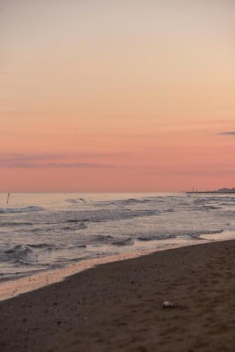 a beach at sunset with the ocean in the background at Hotel Negresco in Lido di Jesolo