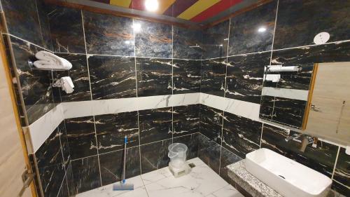 a bathroom with a black and white tiled wall at Nomadic Inn in Dharamshala