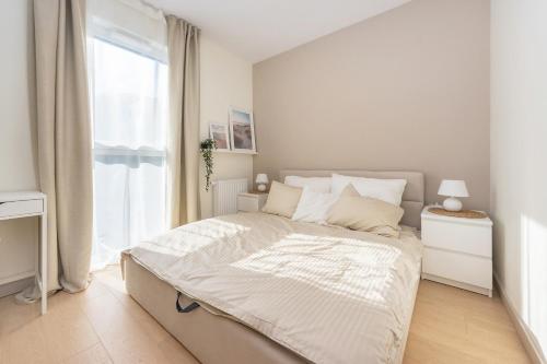 Habitación blanca con cama y ventana en Hello Apartments Letnica with sea view and private parking en Gdansk
