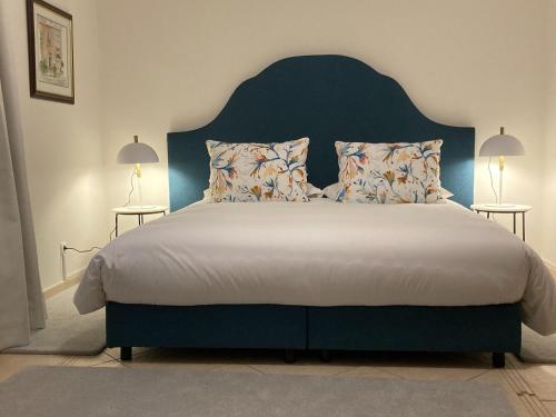 um quarto com uma cama grande e uma cabeceira azul em Villa Tranberg Suites nas Ferreiras
