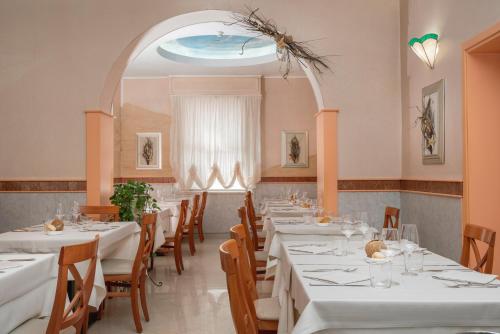 un comedor con mesas blancas y sillas de madera en Albergo Ristorante Pozzi, en Bellaria-Igea Marina