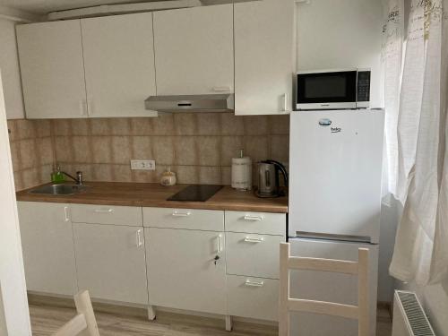 a white kitchen with a refrigerator and a microwave at Baltic Sea Beach Apartment in Liepāja