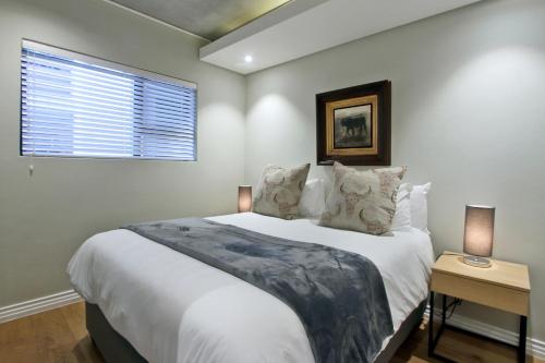 - une chambre avec un grand lit blanc et une fenêtre dans l'établissement Docklands Deluxe One bedroom Apartments, au Cap
