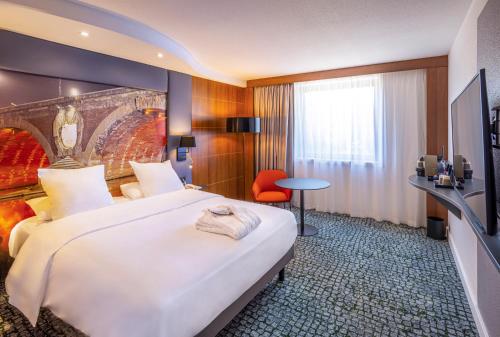 a hotel room with a large bed and a chair at Hotel Mercure Toulouse Centre Compans in Toulouse